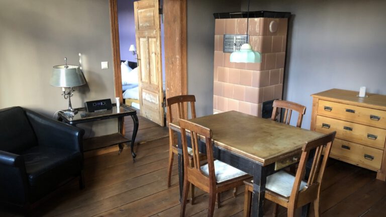Ausziehbarer Esstisch mit Ledersessel und Kachelofen im Hintergrung in der Ferienwohnung suedlich der Mueritz
